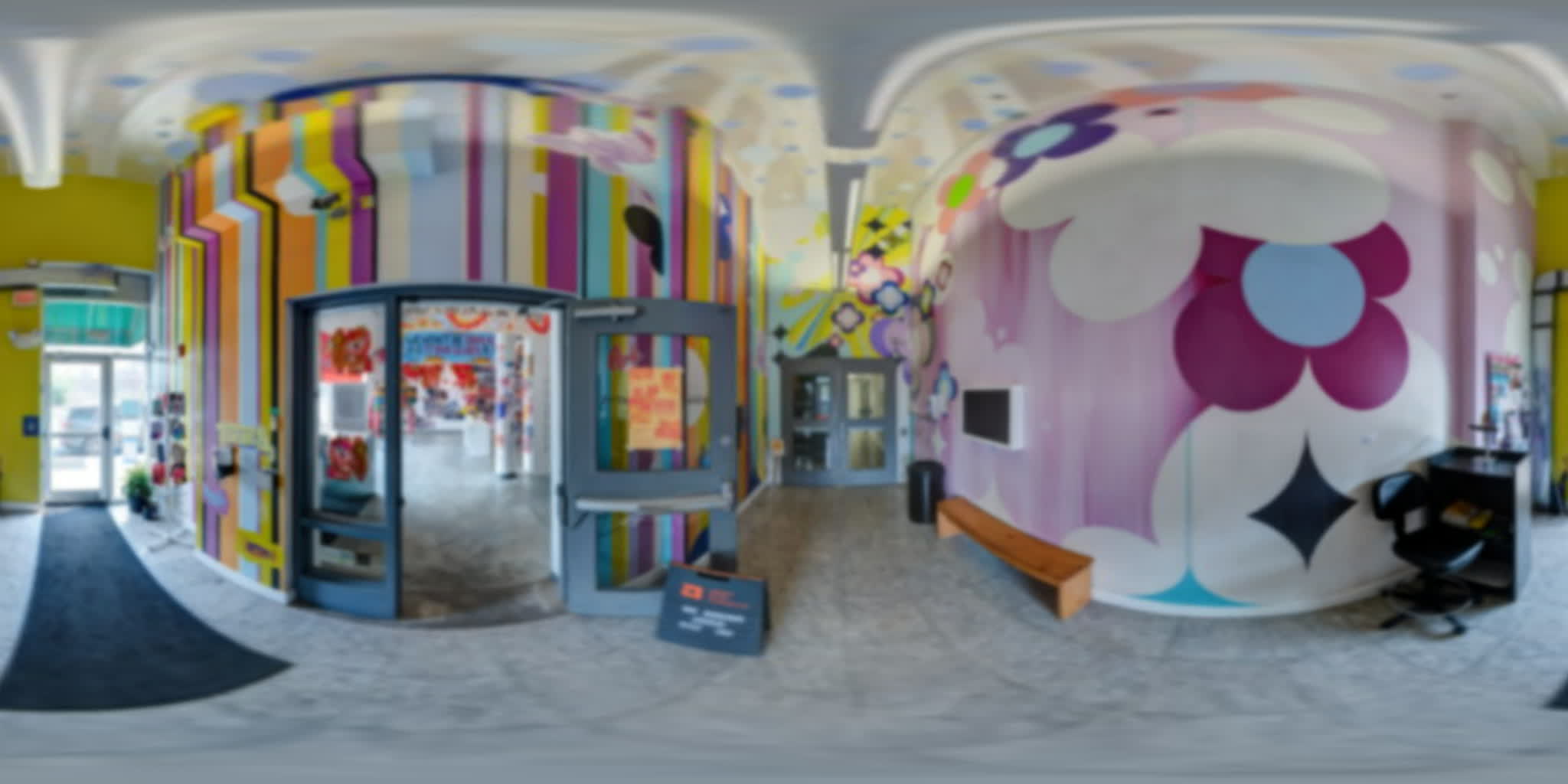 Colorful mural-lined foyer opening into the No Arena exhibition.