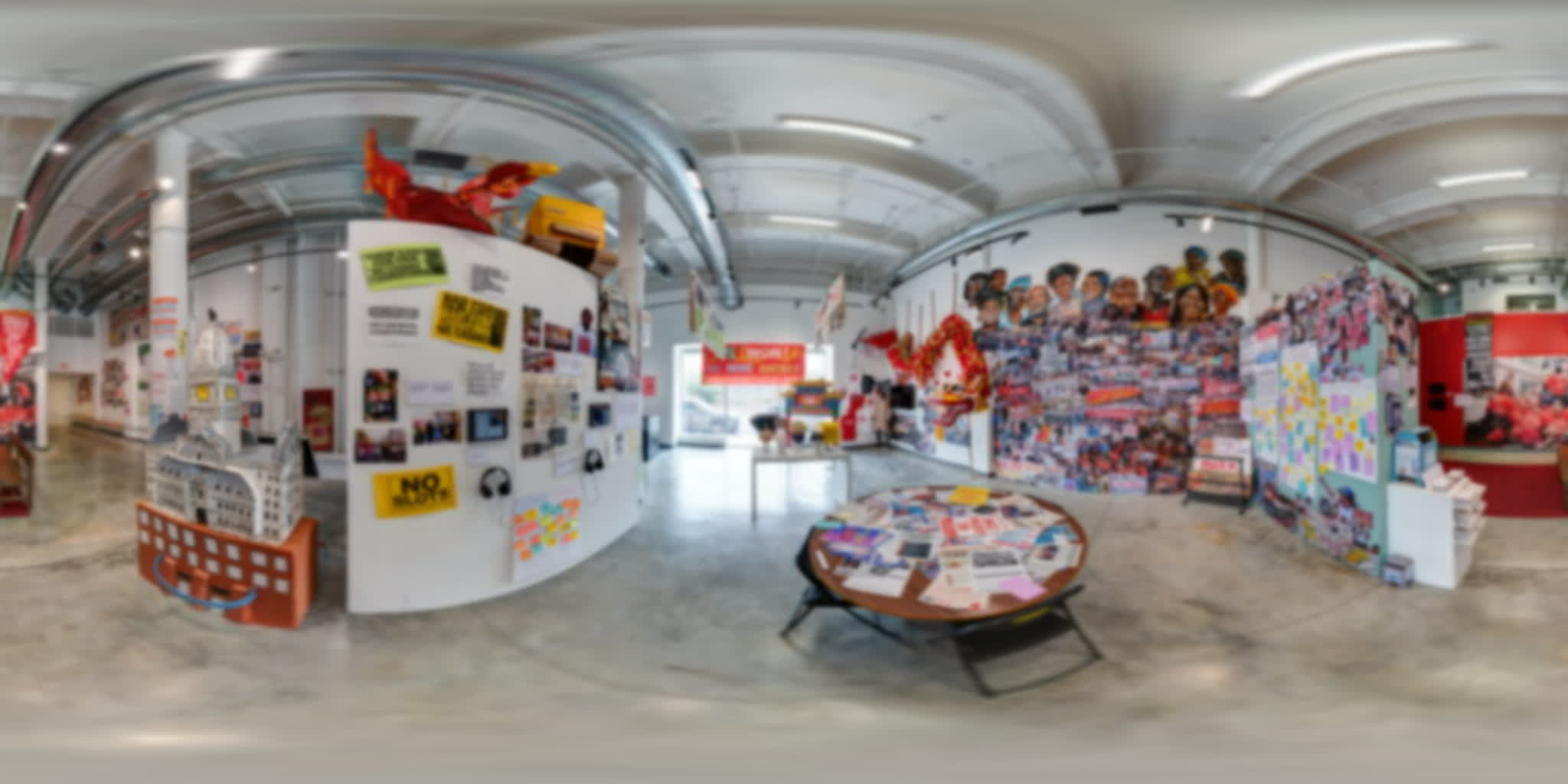 Gallery view filled with protest archives, hand-painted objects, a dragon, and gathering spaces.