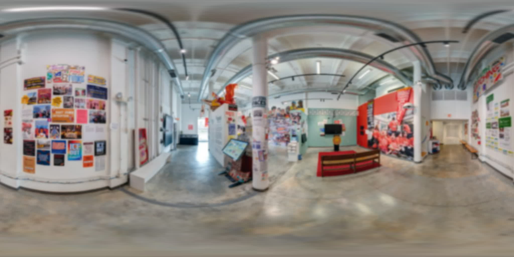 Two wall-mounted screens with headphones beside an interactive exhibition kiosk.