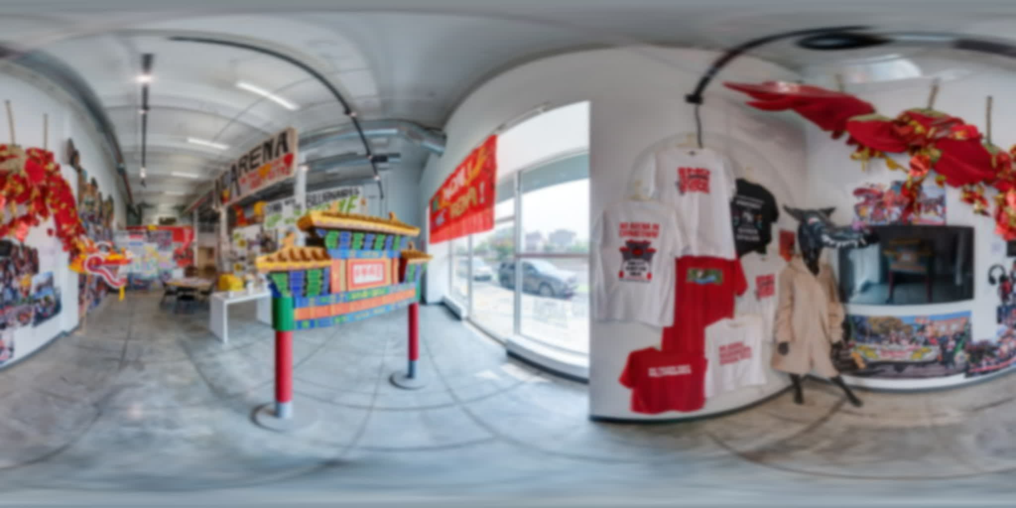 Gallery wall with a large screen, headphones, shirts, dragon imagery, and gathering spaces.