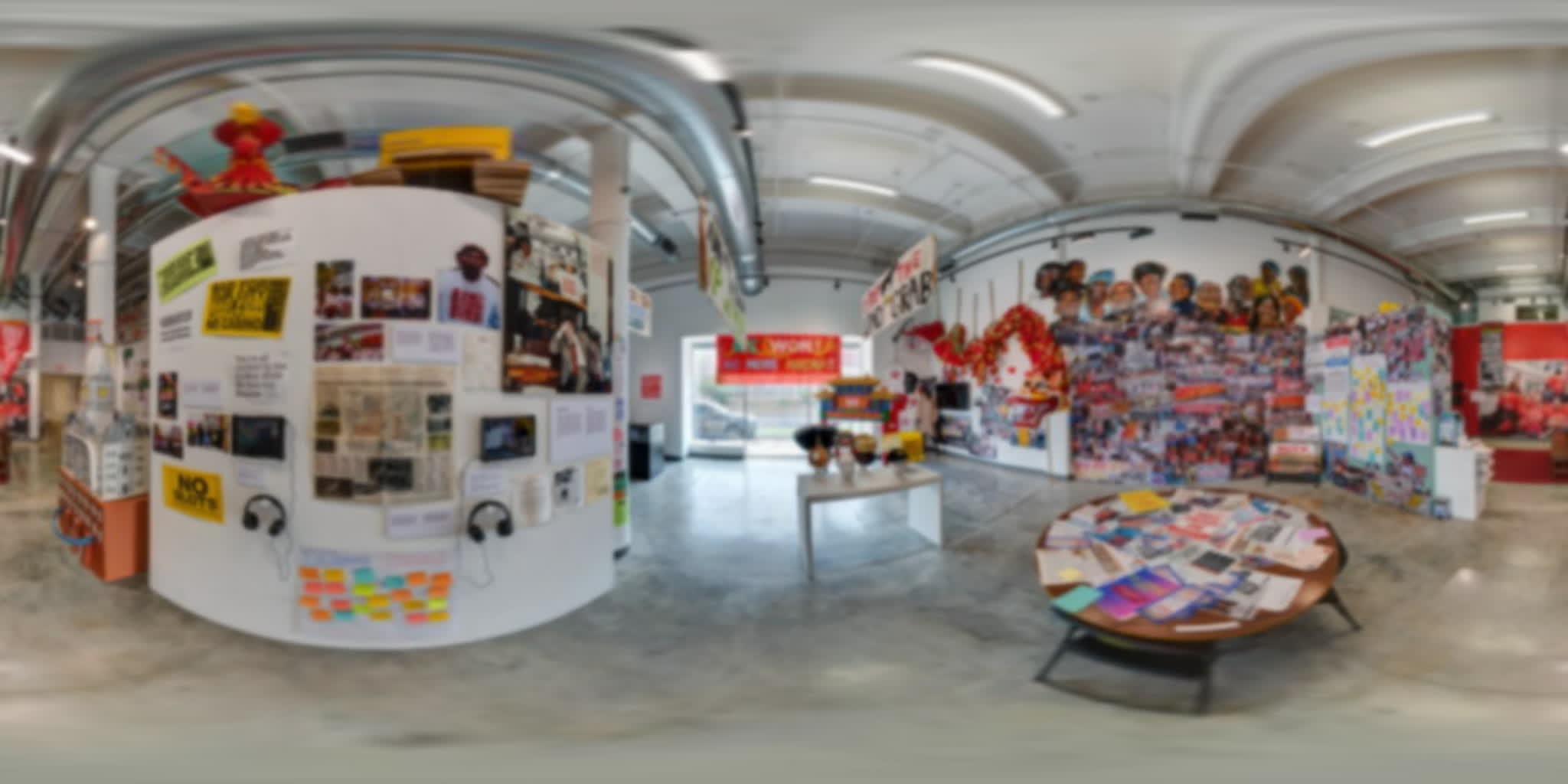 Curved archive wall with two tablet screens, listening stations, campaign photographs, and handwritten notes.