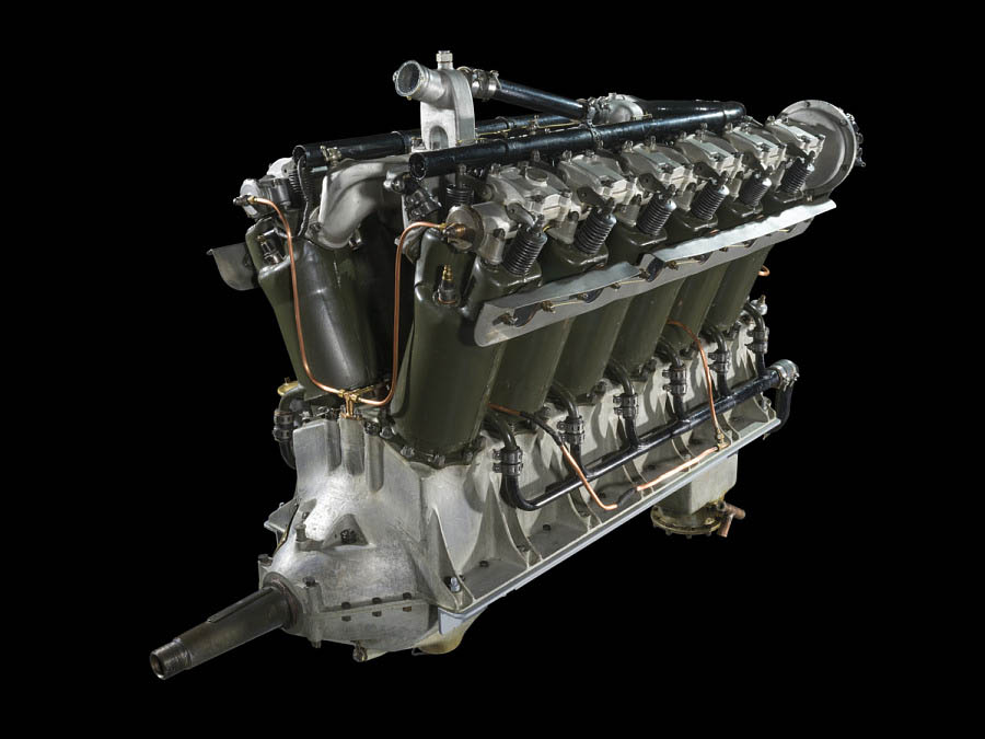 Twelve-cylinder reciprocating engine with an aluminum crankcase, dual carburetors, and two banks of green cylinders.