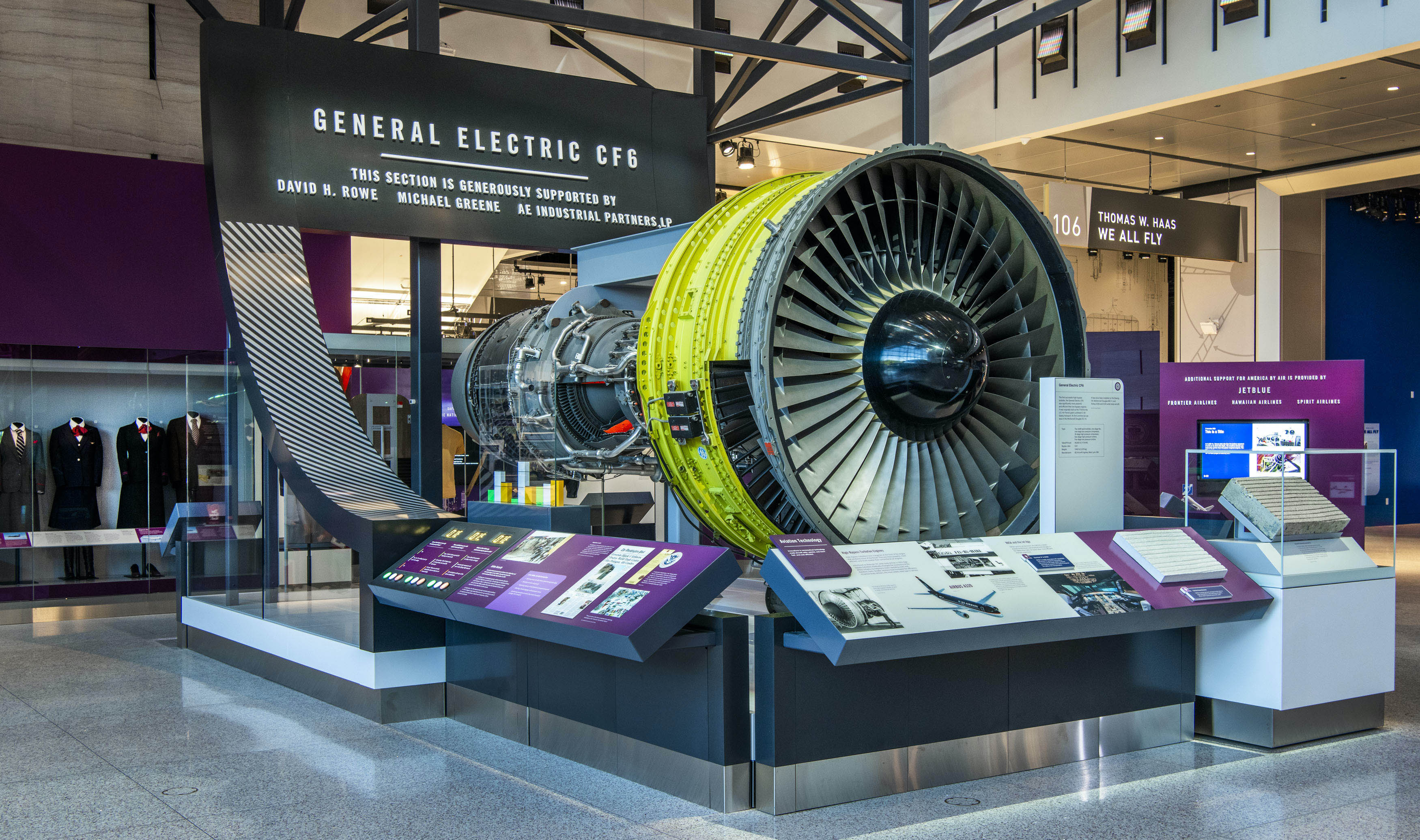 Cutaway high-bypass turbofan with metal fan blades, a yellow-green fan case, and red combustor section.