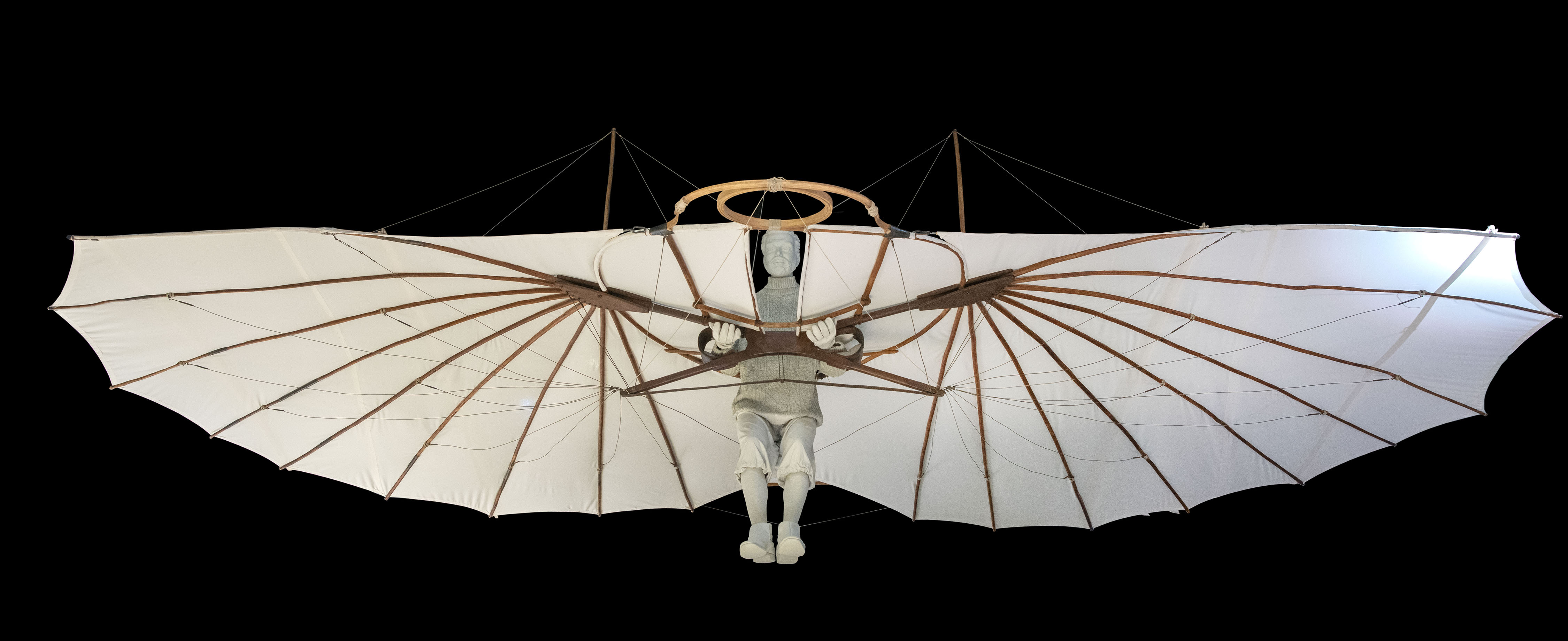 A fabric-covered monoplane glider with exposed wooden ribs and a circular frame where the pilot shifted body weight to control flight.