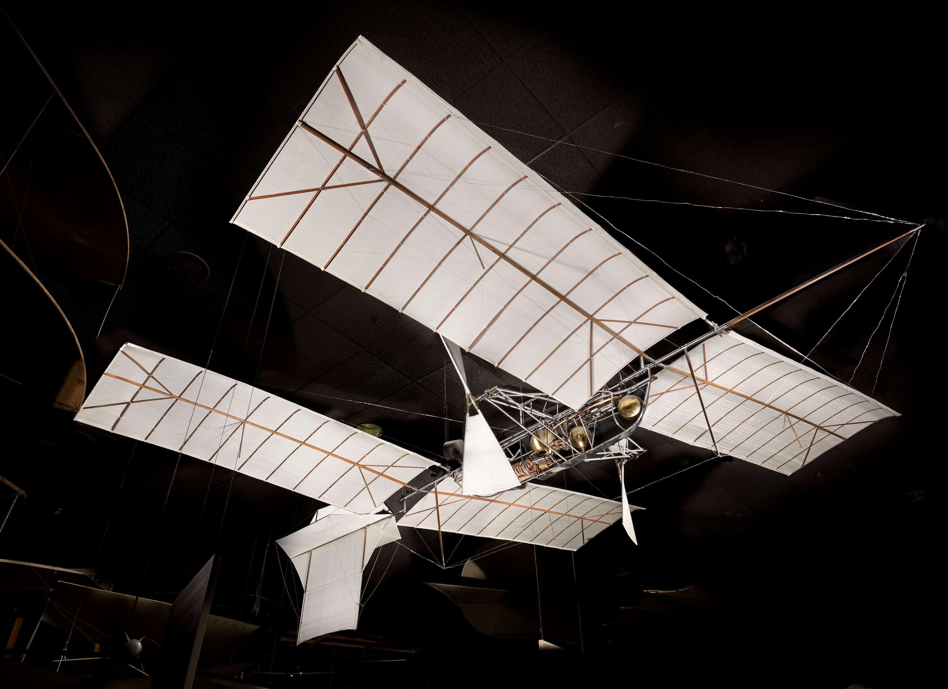 An unmanned tandem-wing aircraft with silk-covered wings, exposed ribs, twin pusher propellers, and a steam engine in an open metal fuselage.