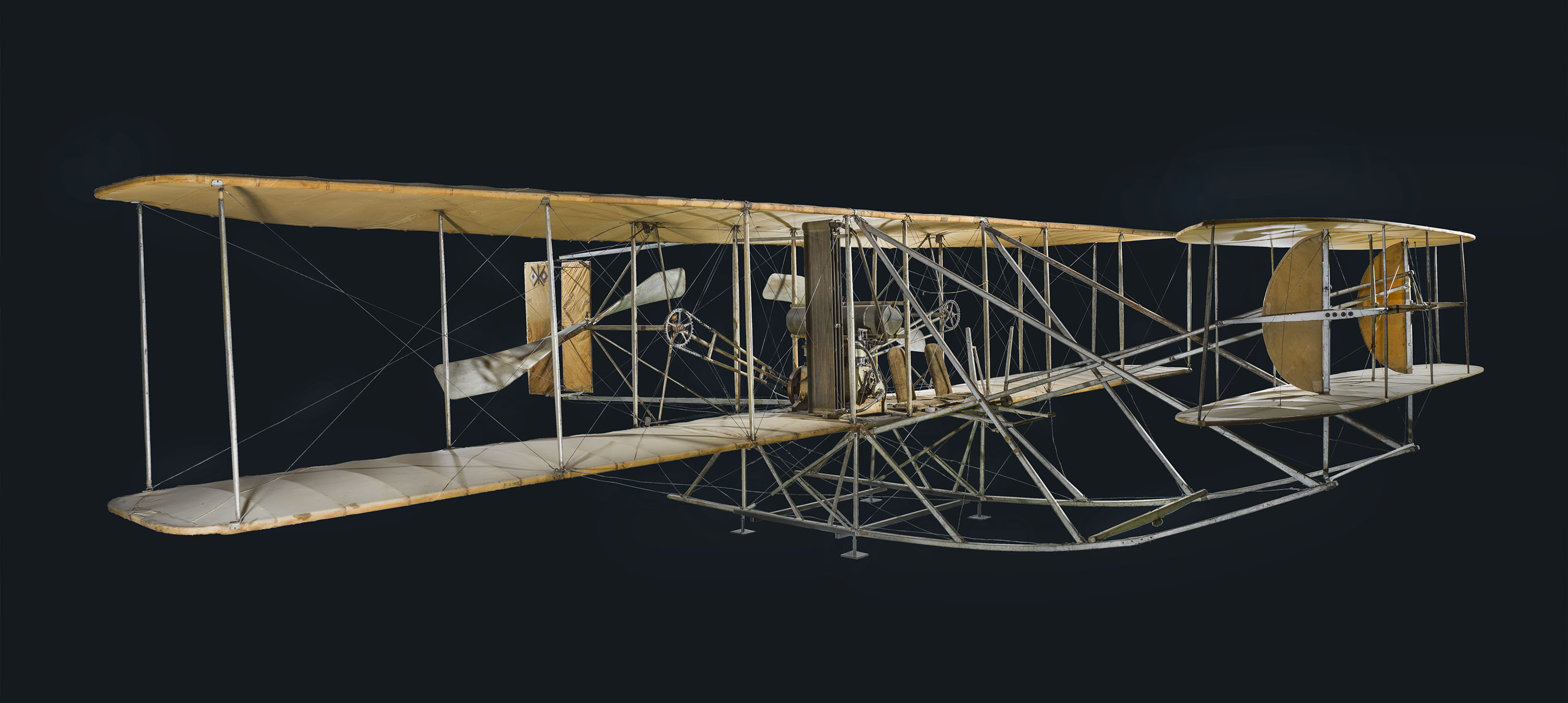 A two-seat canard biplane with twin rear-facing propellers, chain drives, landing skids, fabric wings, and a forward elevator.