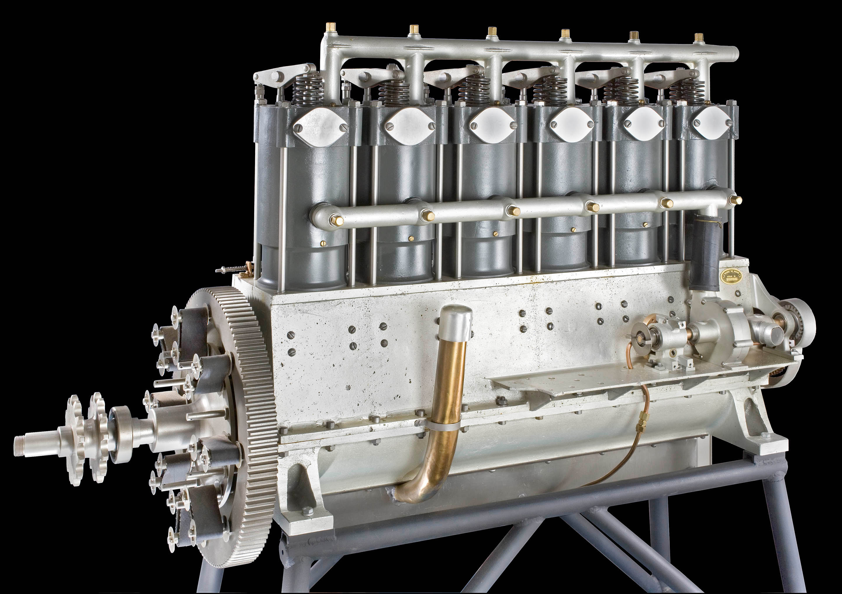 A tall six-cylinder water-cooled inline engine with dual carburetors and a flexible flywheel drive.