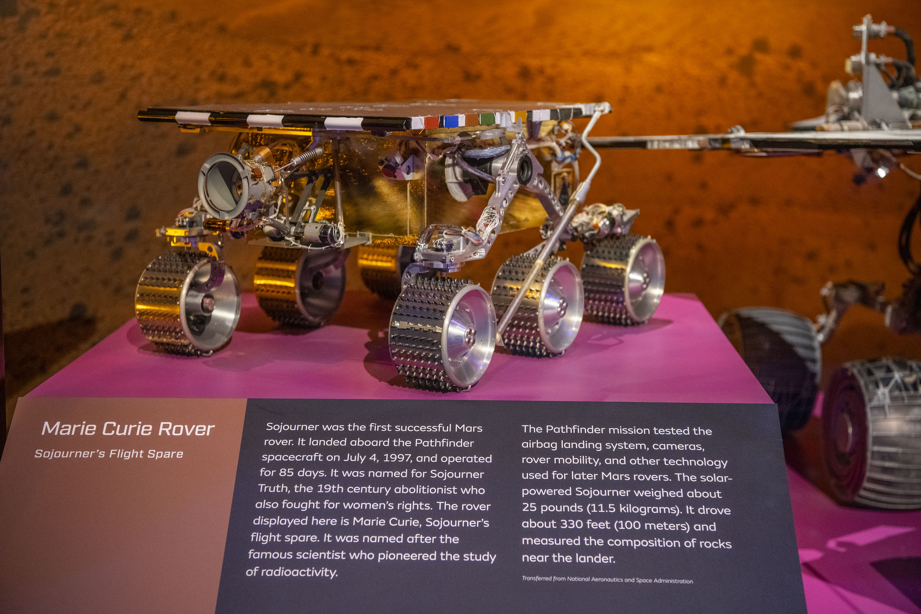 Small gold-covered six-wheeled rover with solar panels, cameras, and an instrument mounted at the rear.