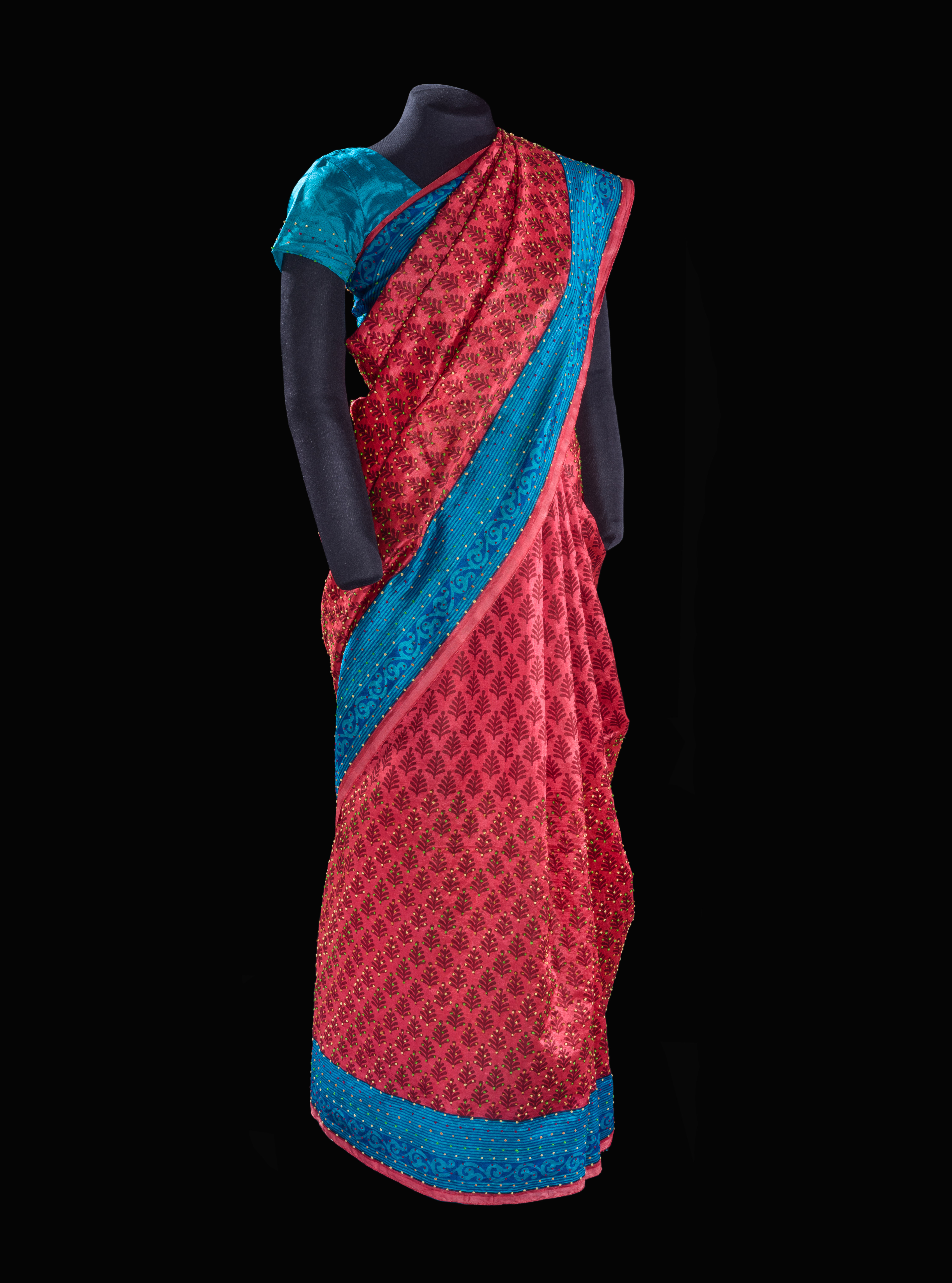 A red-and-blue silk-and-cotton saree draped over a dark mannequin.