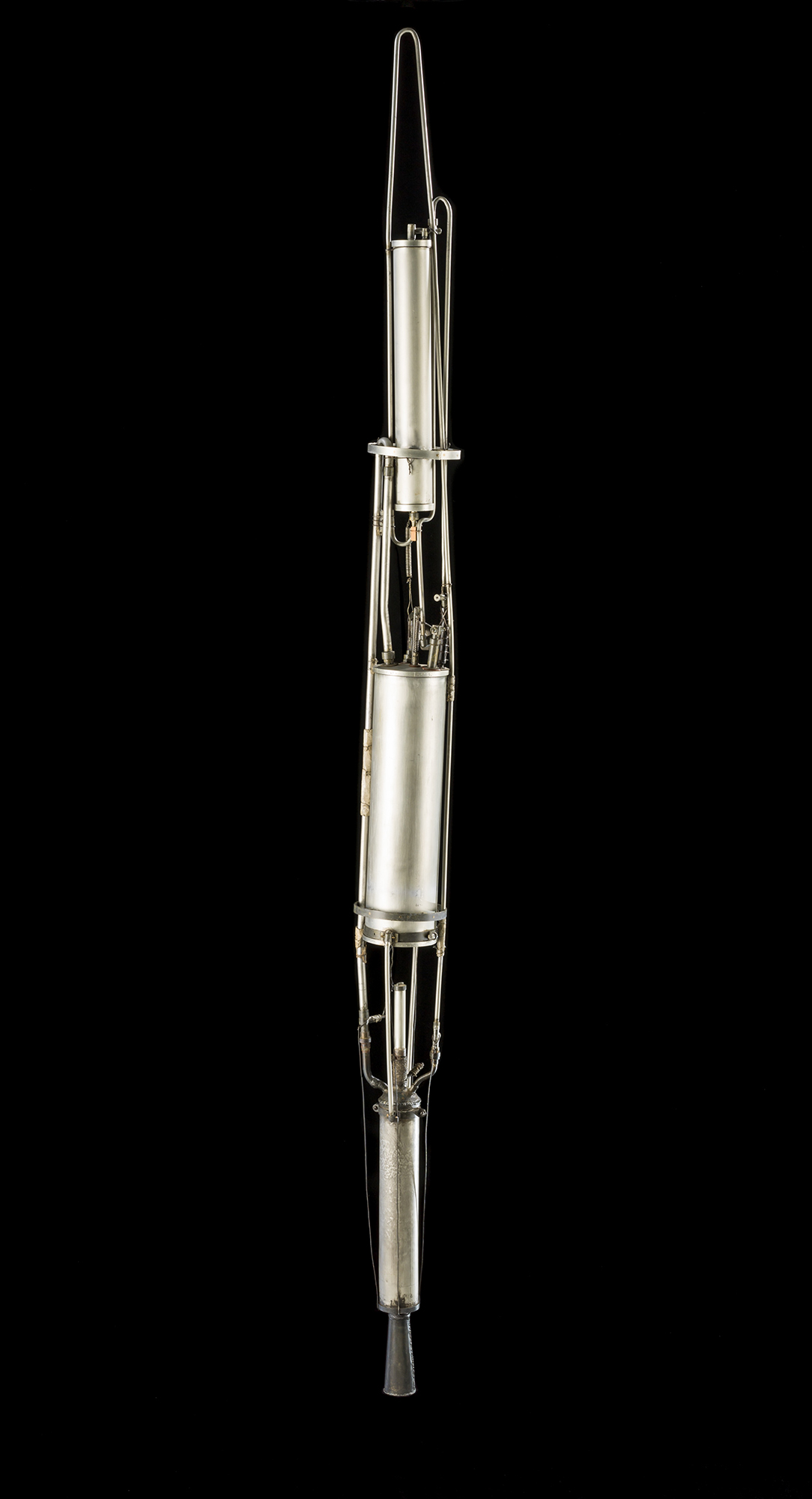 A slender silver liquid-fueled rocket made of cylindrical sections joined by fine rods, with a pointed top.