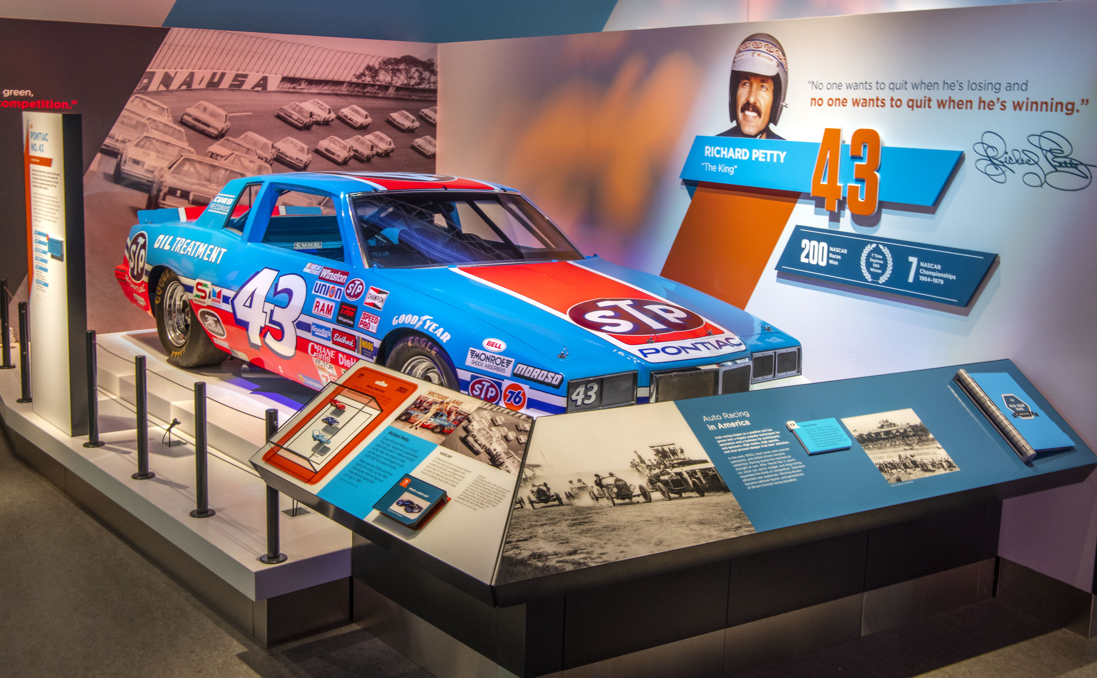 Red and blue stock car covered with sponsor marks and large white number 43 numerals.