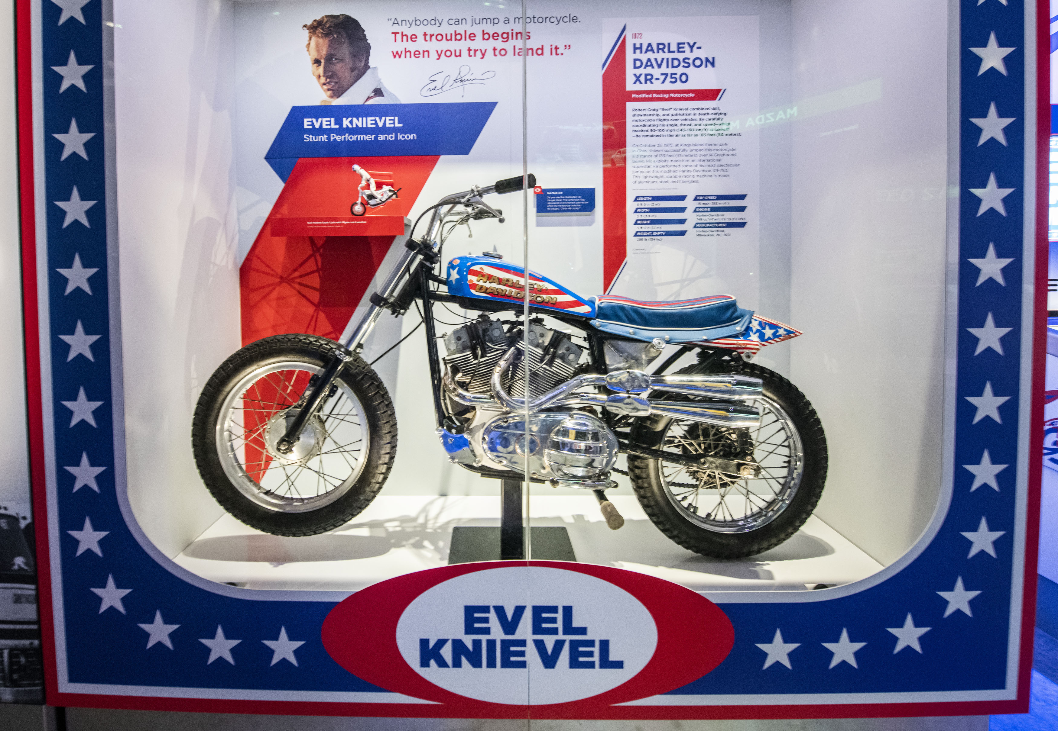 Silver motorcycle with red, white, and blue seat and fairings decorated with stripes, stars, and Harley-Davidson lettering.
