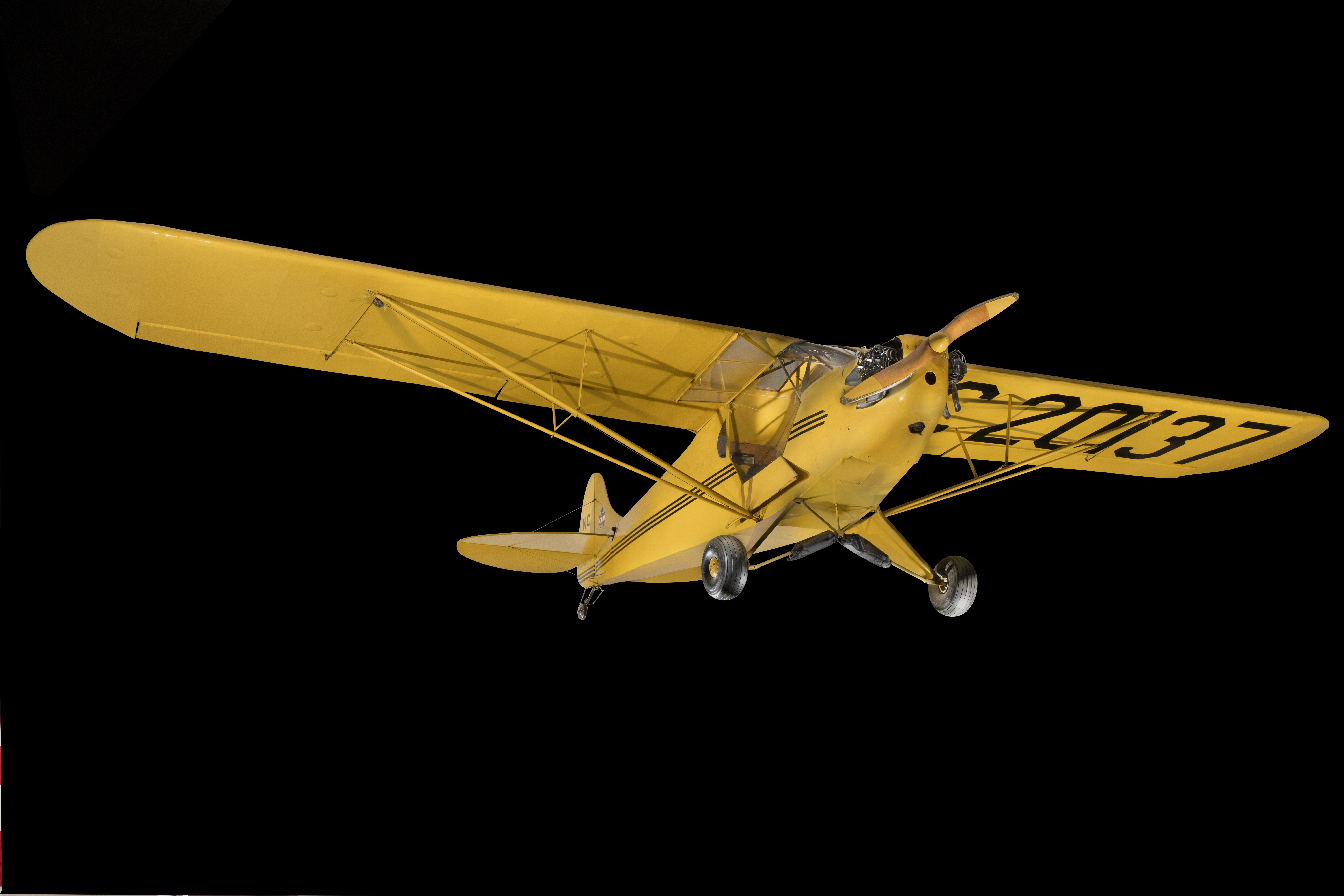 Yellow and black, high-wing Piper J-2 Cub light airplane with a small Continental engine.