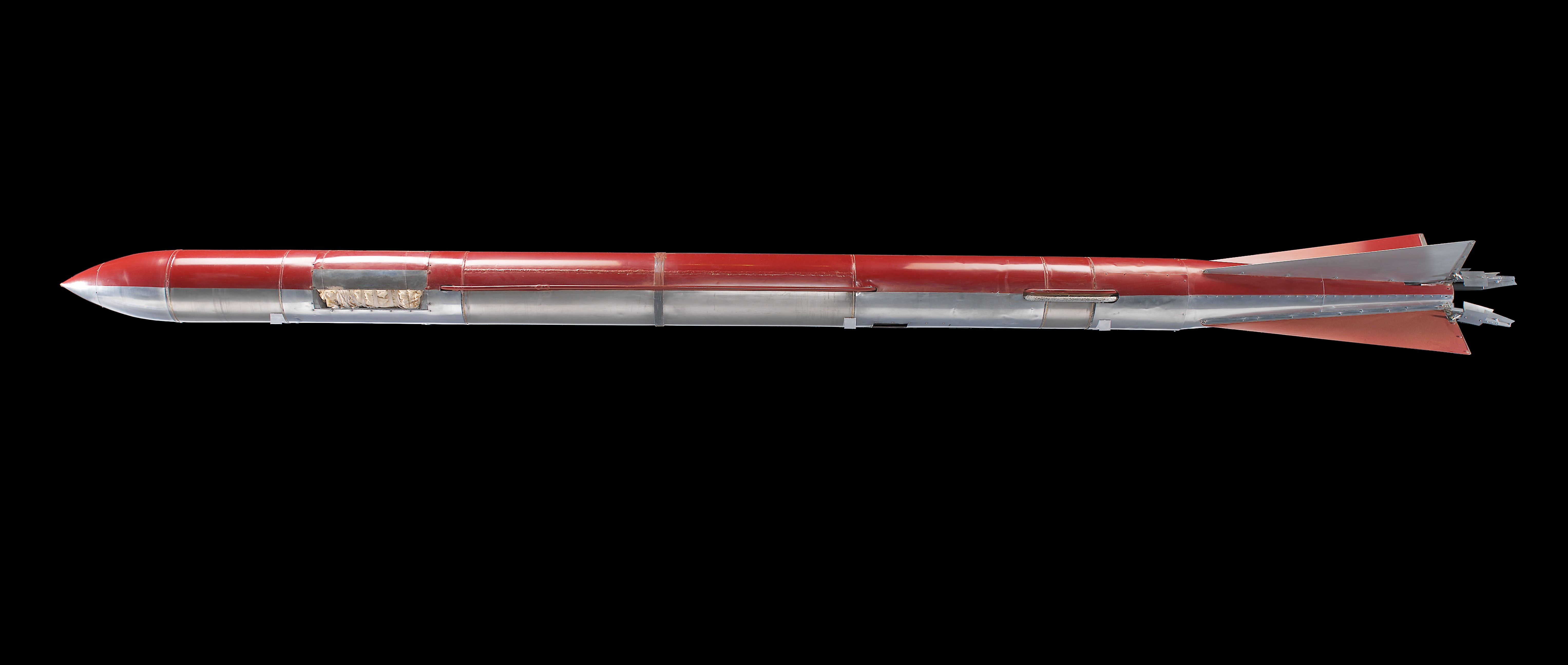 Slender metal liquid-fueled rocket with fins, propellant section, external tubing, and a pointed nose.
