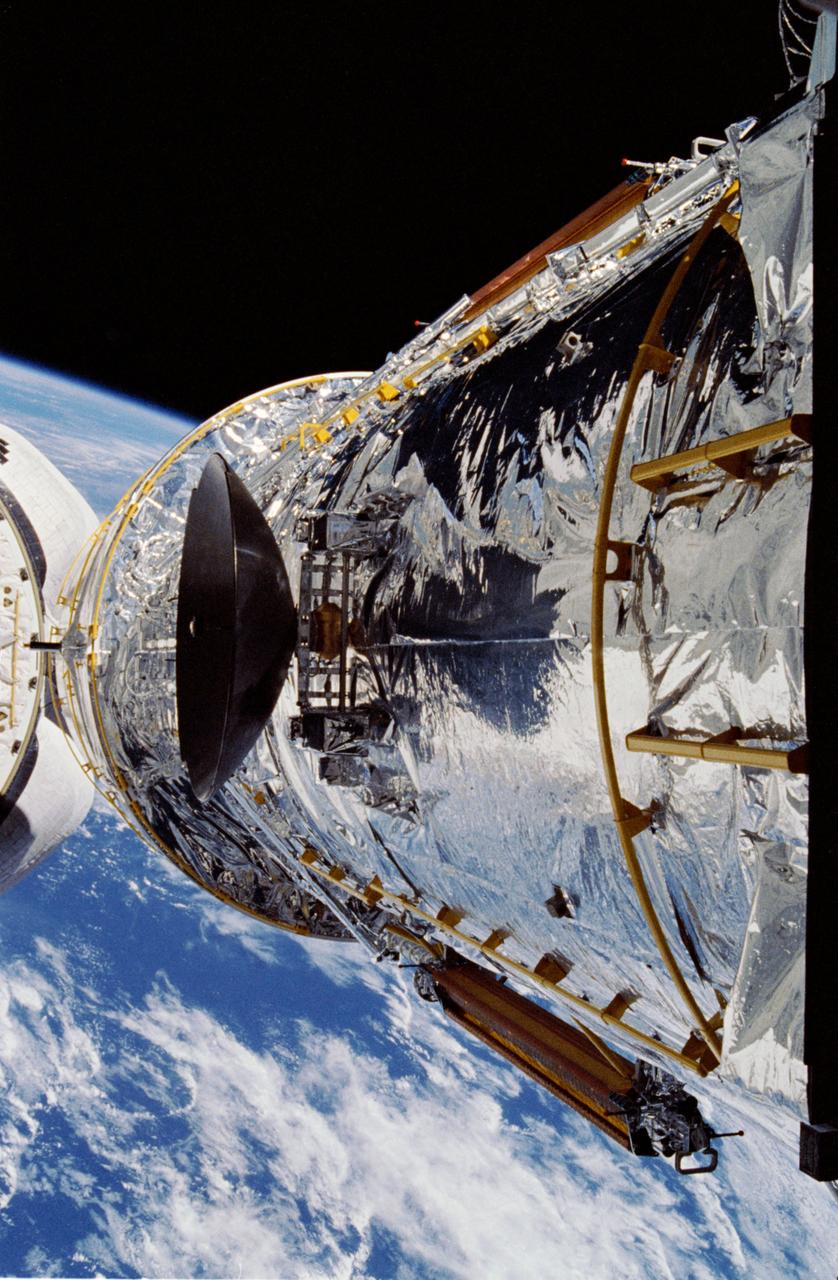 Discovery’s robotic arm raises Hubble above the payload bay during STS-31 deployment preparations in 1990.