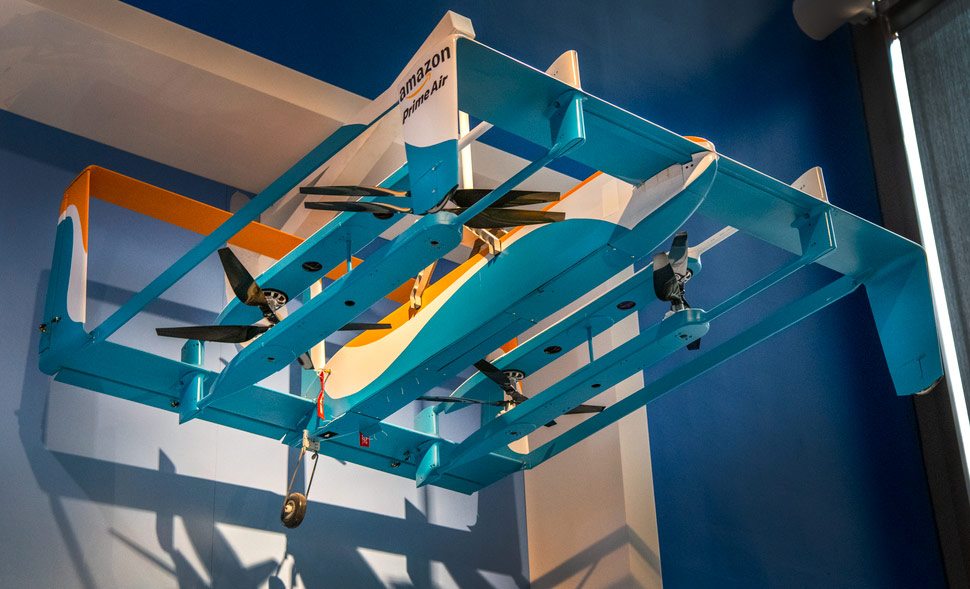 Large light-blue delivery drone with lifting rotors, fixed airfoils, wheels, and a raised tail.