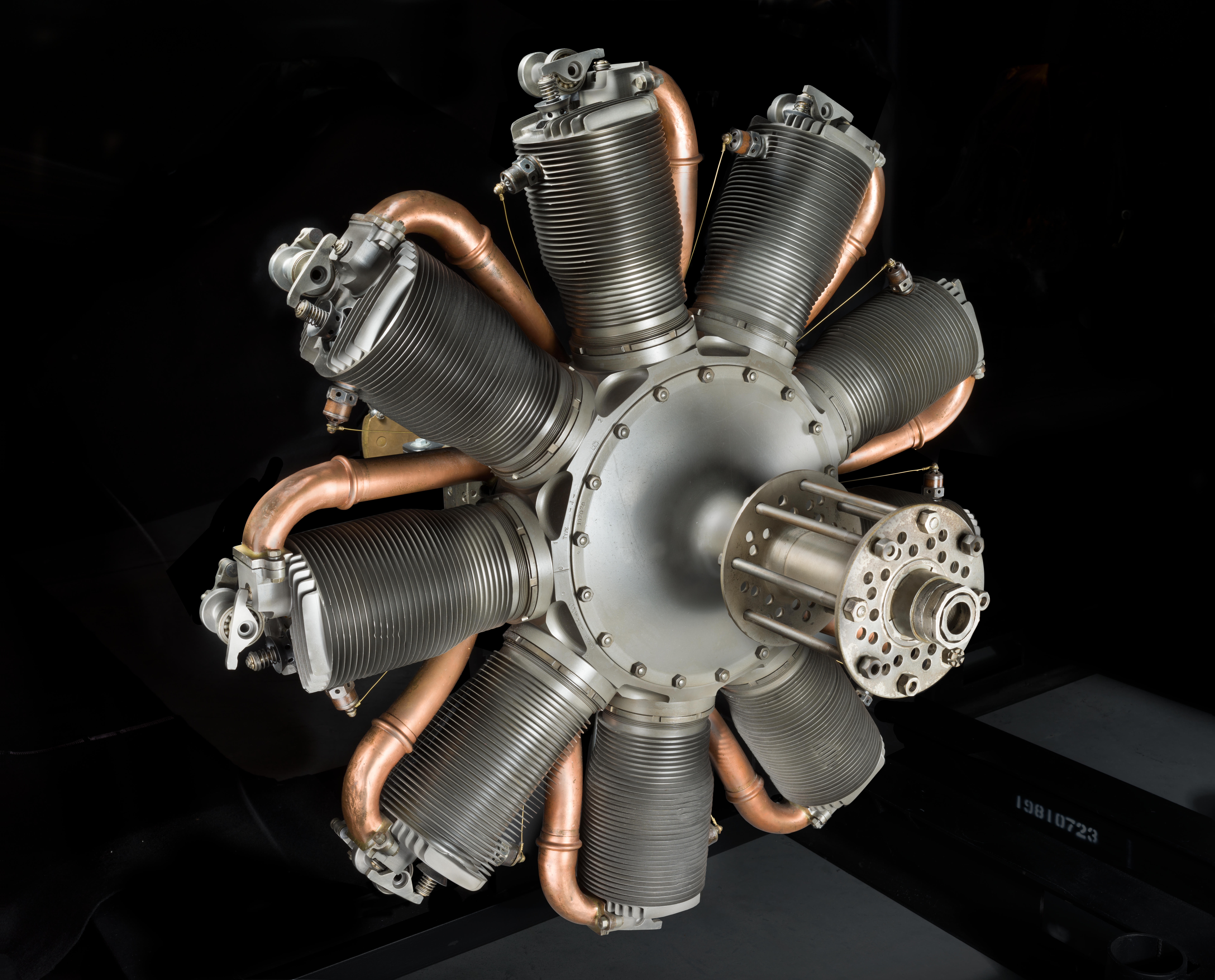 Circular nine-cylinder Le Rhône rotary engine with silver cylinders around a central hub.