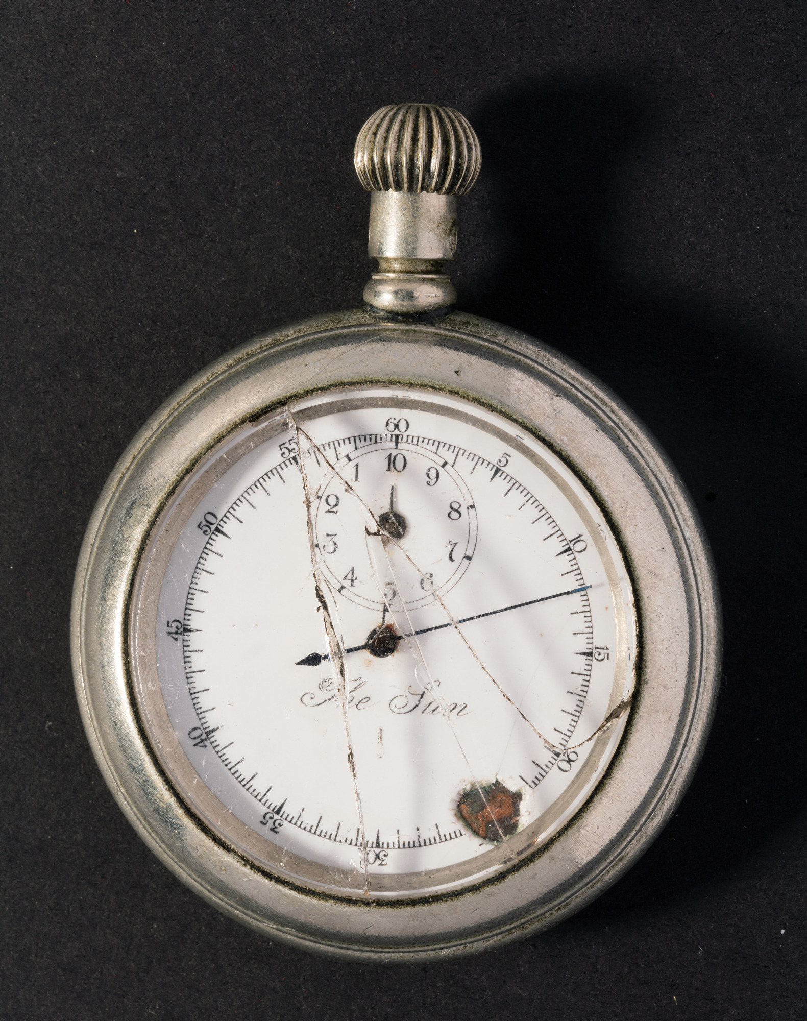 Nickel-plated hand-held stopwatch with a white face, black numerals, a small minute dial, and cracked glass.