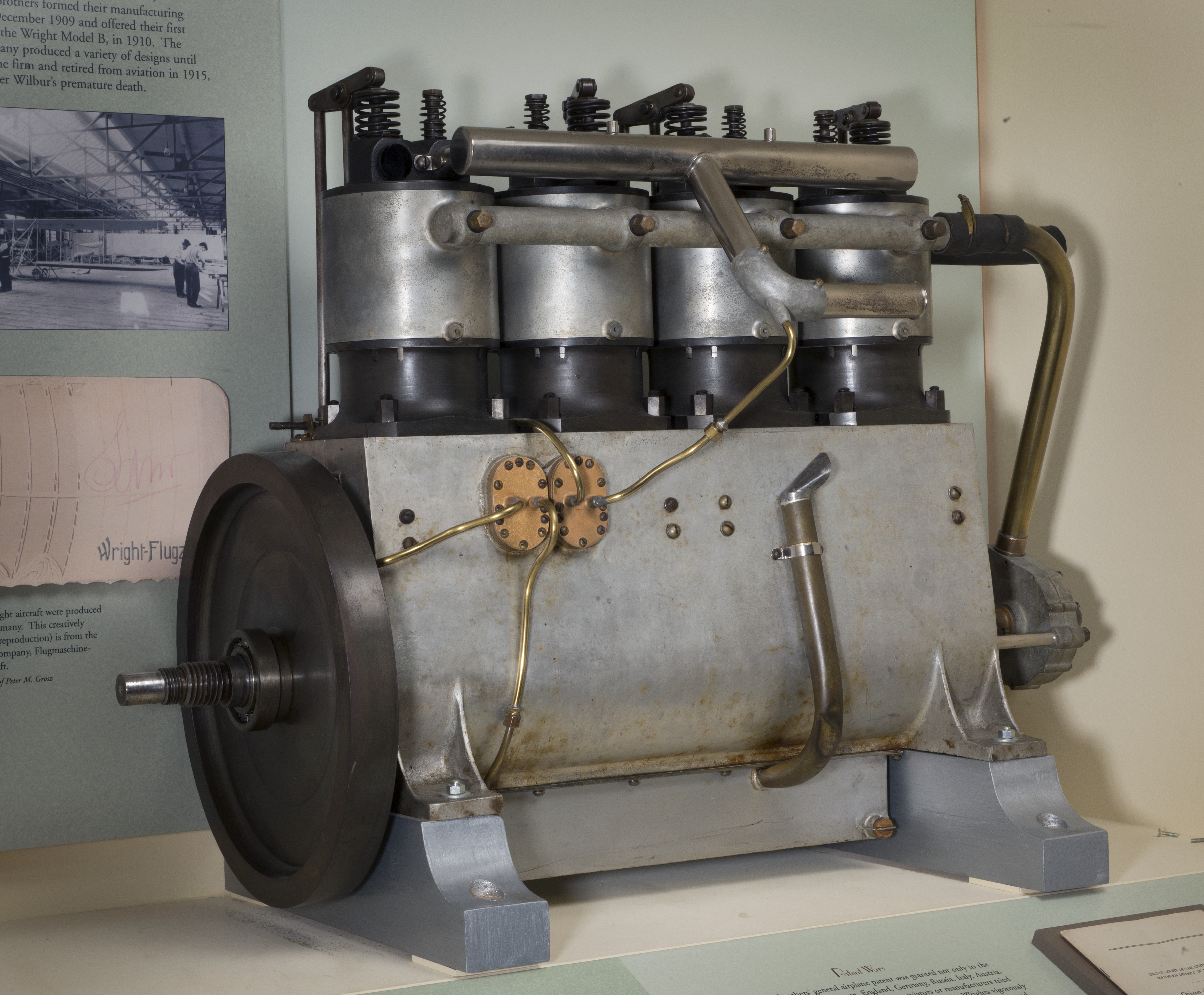 Silver inline four-cylinder, water-cooled aircraft engine with exposed mechanical components.