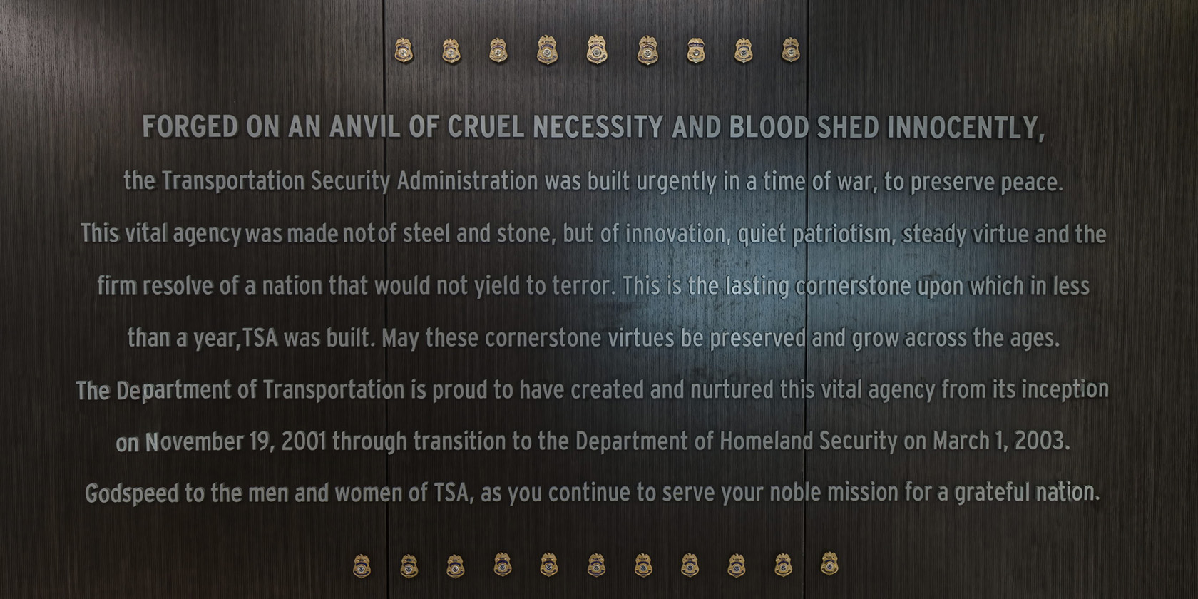Cornerstone wall displaying a mission statement and a field of badges